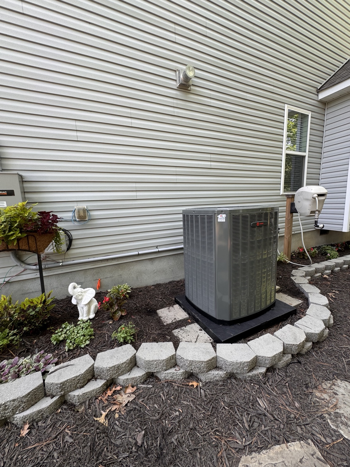 Finished Trane heat pump installation with a landscaped equipment area