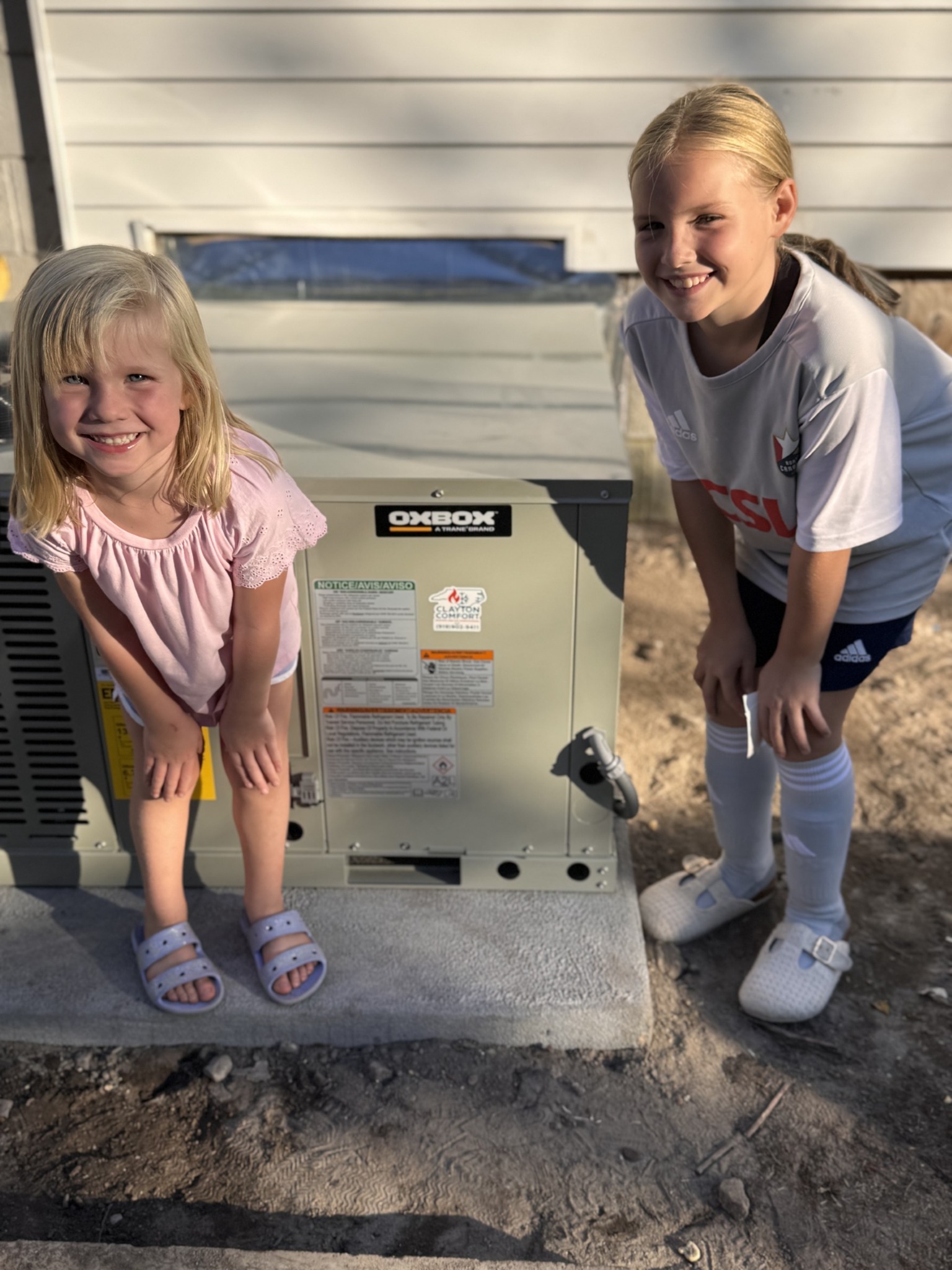 Young family members beside an OXBOX unit during a local installation